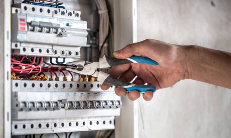 Man, an electrical technician working in a switchboard with fuses. Installation and connection of electrical equipment. Close up.